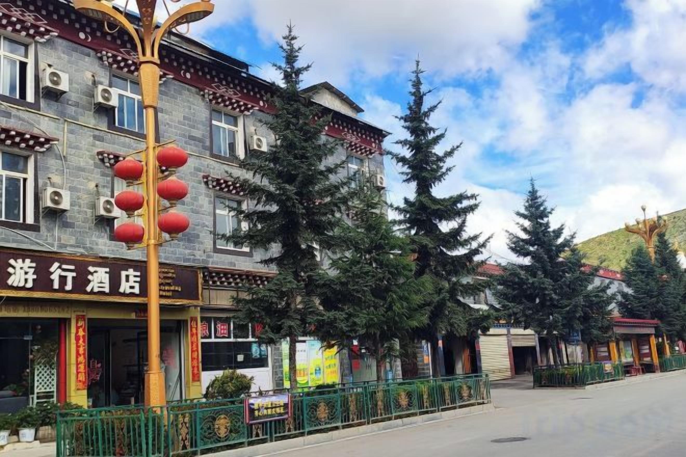 A hotel with traditional architecture, a green fence, and red lanterns.