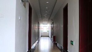 Ein langer, schmaler Gang mit hellem Boden und roten Türen an beiden Seiten.