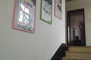 A staircase with a handrail and a wall with framed posters. - Shangri-La Ziyouxing Hotel (Deqin)