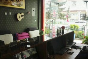 A room with a desk, a guitar, and a window with a view of the street.