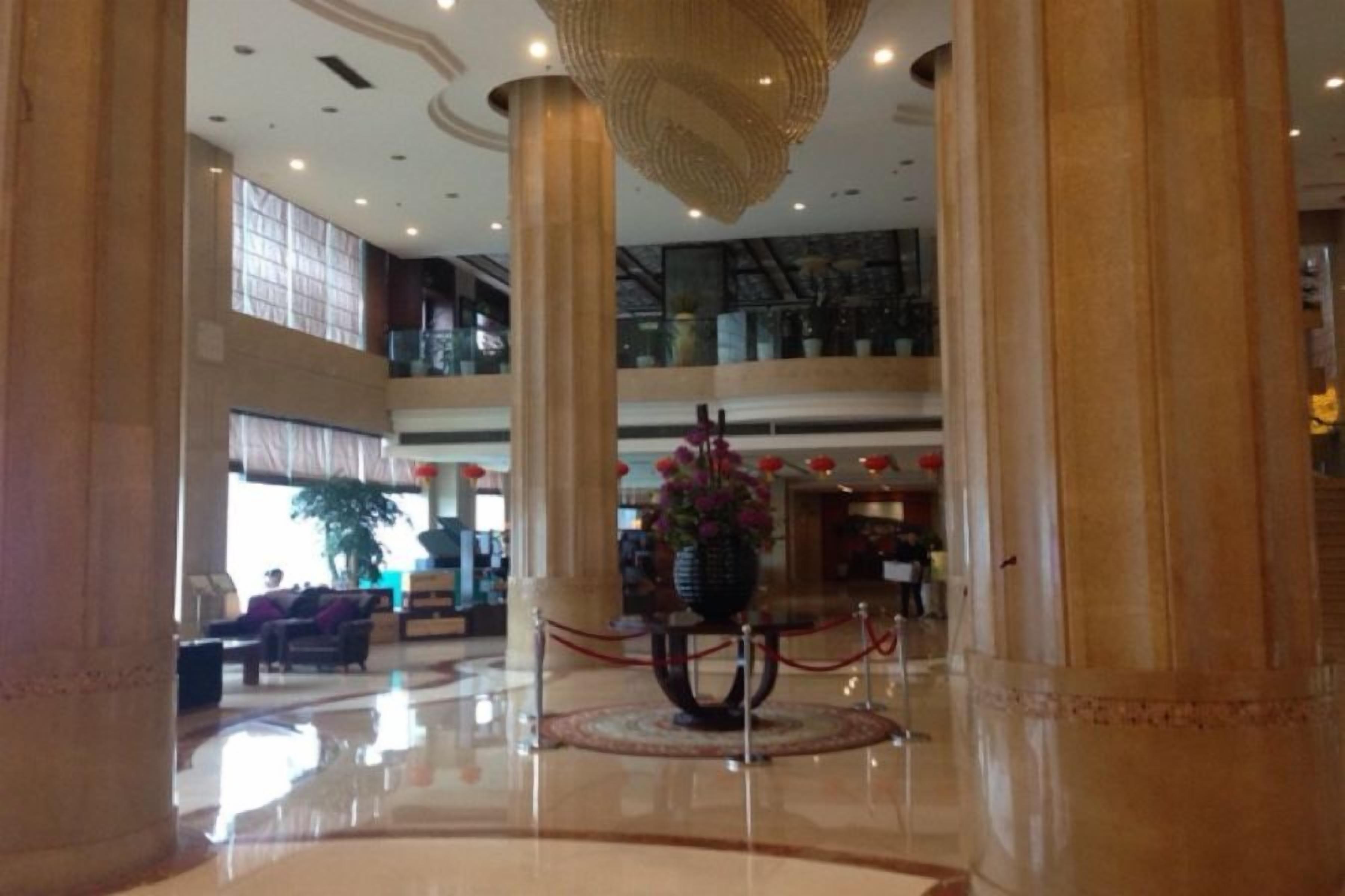 A spacious lobby with high ceilings, large columns, and a central decorative fountain.