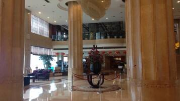 A spacious lobby with high ceilings, large columns, and a central decorative fountain.