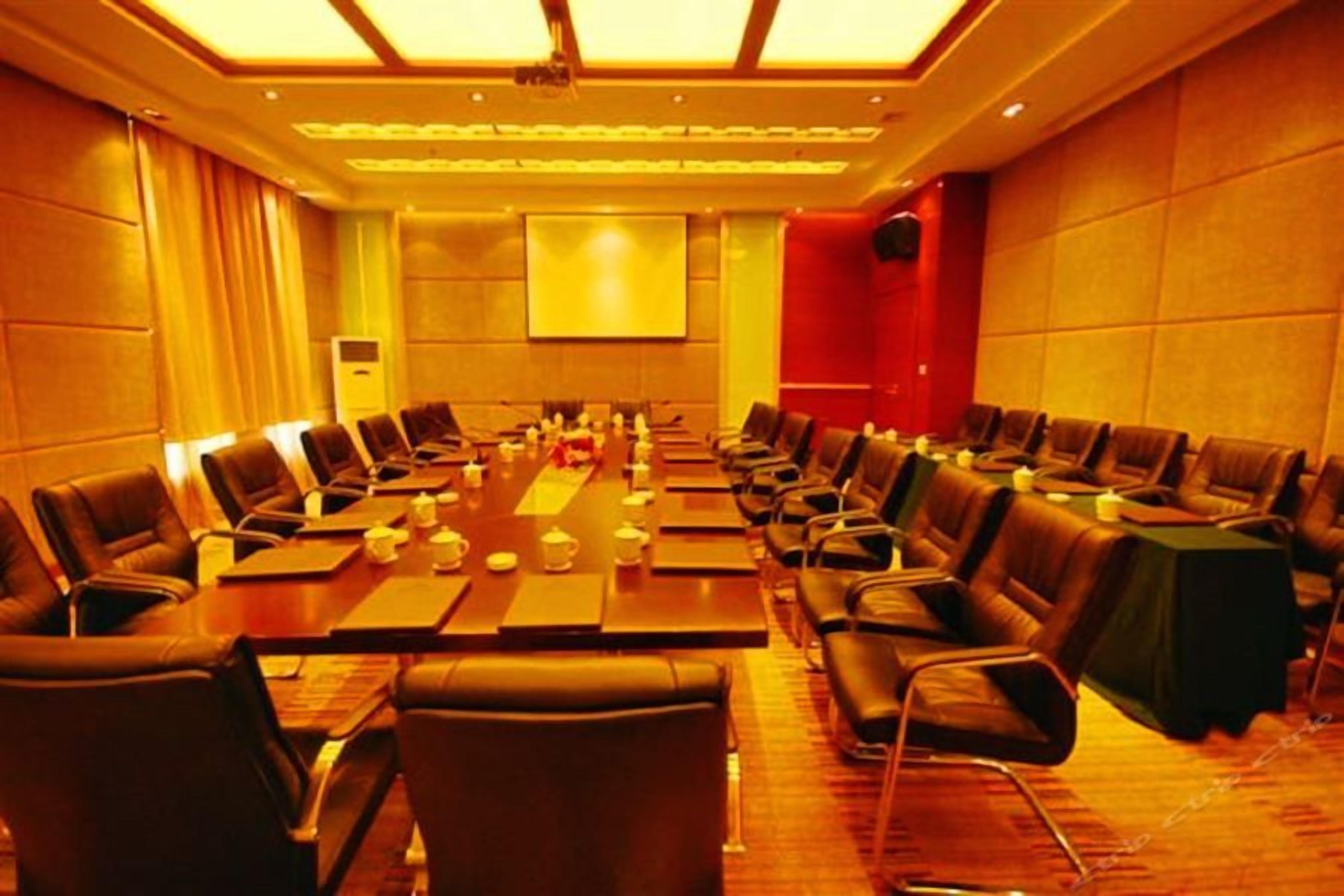 Un salón de conferencias con una mesa larga, varias sillas y una pantalla para proyector.