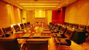 Un salón de conferencias con una mesa larga, varias sillas y una pantalla para proyector.