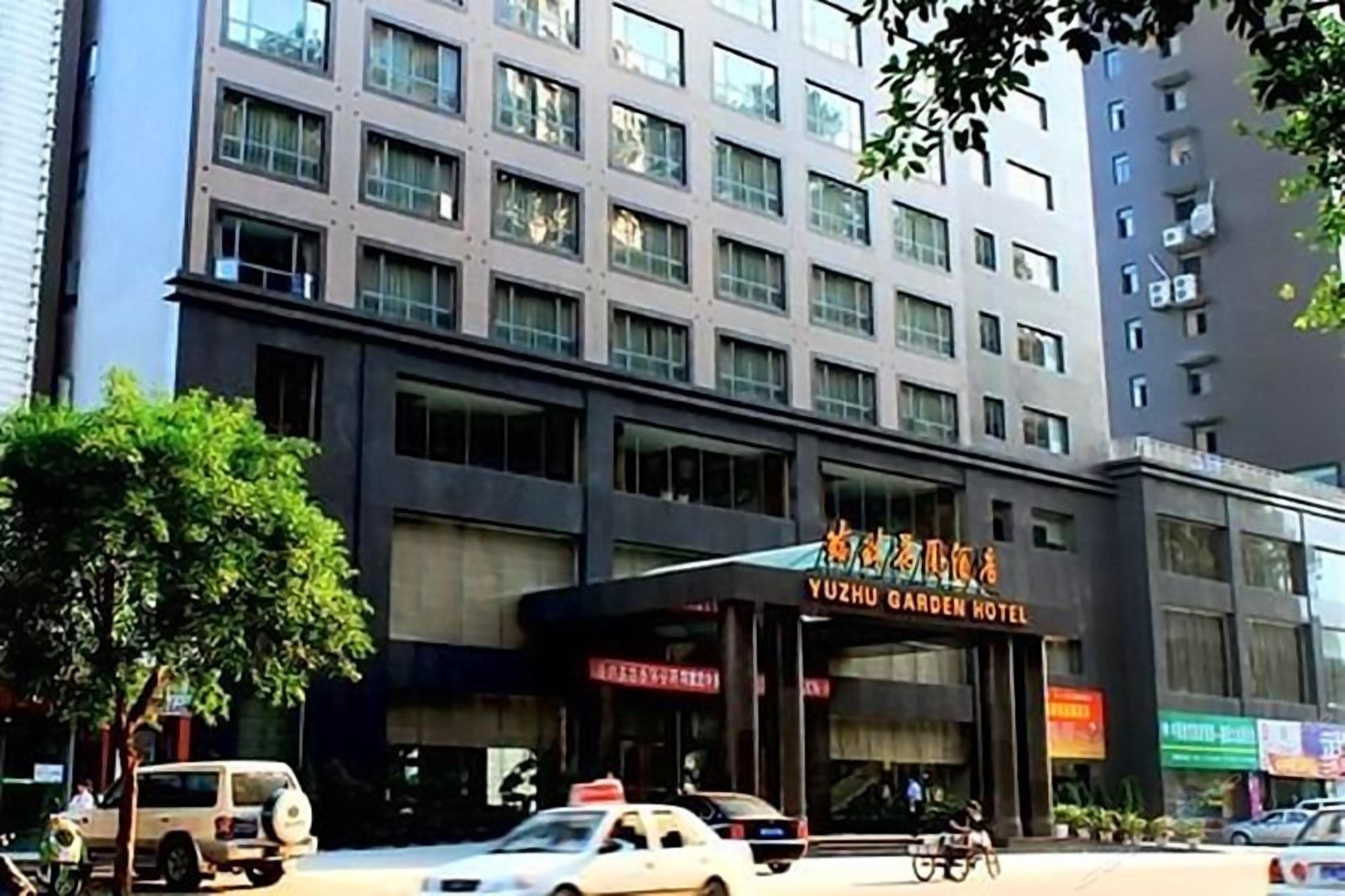 Un edificio de varios pisos con un letrero llamativo del Hotel Yuzhu Garden.