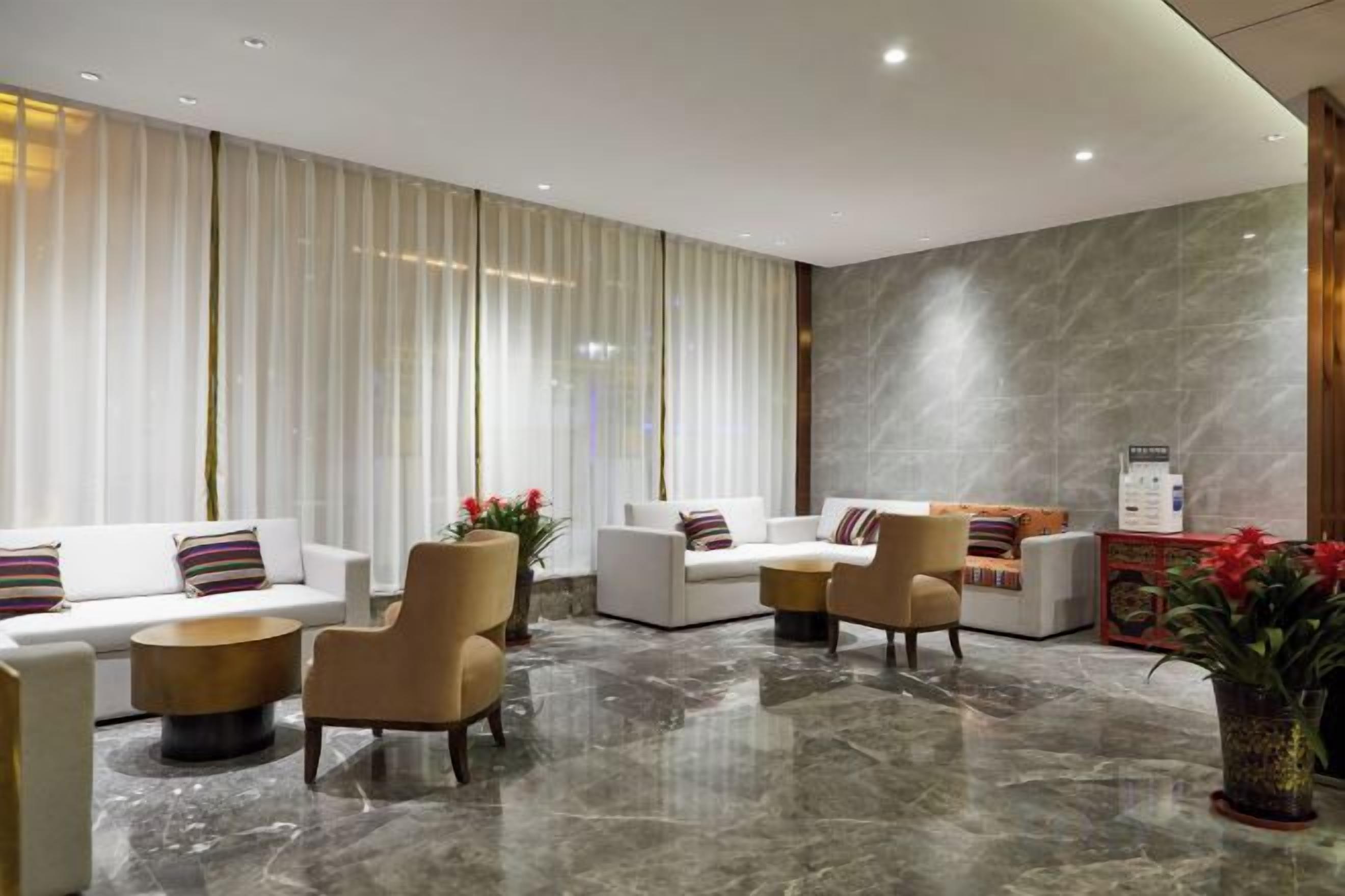 A modern lobby with a marble floor, white sofas, and a reception desk.