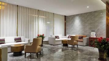 A modern lobby with a marble floor, white sofas, and a reception desk.