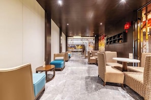 A hotel lobby with seating arrangements, a reception area, and a view into the restaurant. - Jingu Hotel (Lhasa)