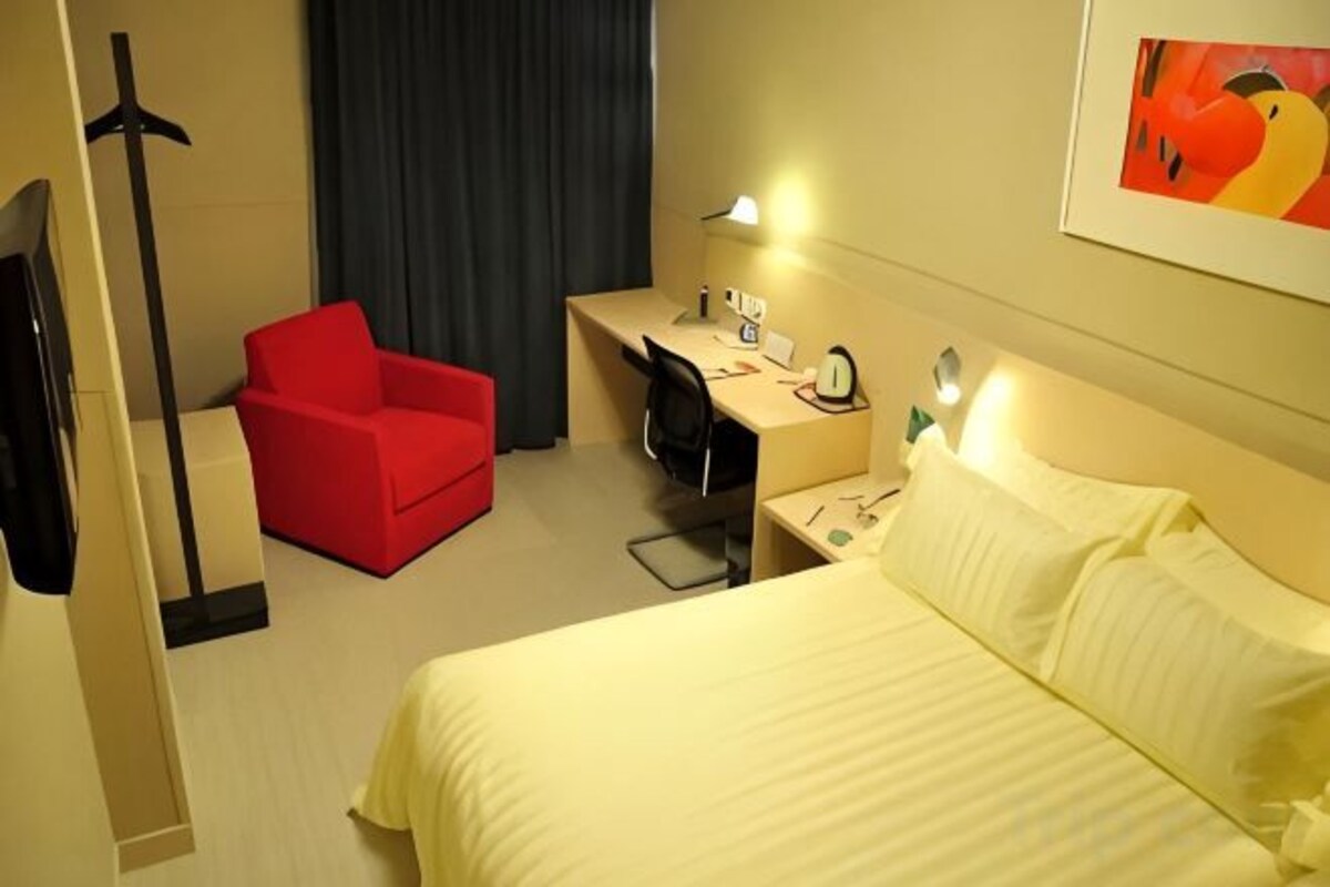 Een hotelkamer met een bed, een bureau, een stoel, een televisie en een schilderij aan de muur.