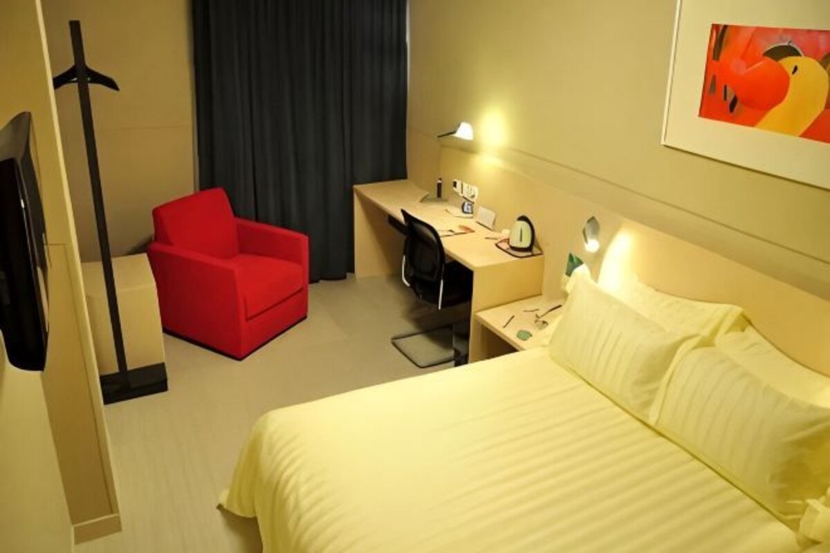 Une chambre d’hôtel avec un lit, un bureau, une chaise, une télévision et un tableau au mur.