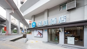 A hotel with a sign indicating it is a hotel. There is a pedestrian crossing sign and a road with a barrier. - Hanting Express Zhongshaner Road (Guangzhou)