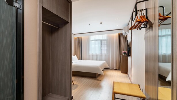 A hotel room with a bed, a bench, a mirror, and a coat rack. - Hanting Express Zhongshaner Road (Guangzhou)