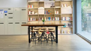 A library with bookshelves, a wooden table, and bar stools. - Hanting Express Zhongshaner Road (Guangzhou)