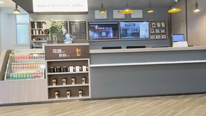 A modern coffee shop interior with a counter, beverage display, menu boards, and digital screens. - Hanting Express Zhongshaner Road (Guangzhou)