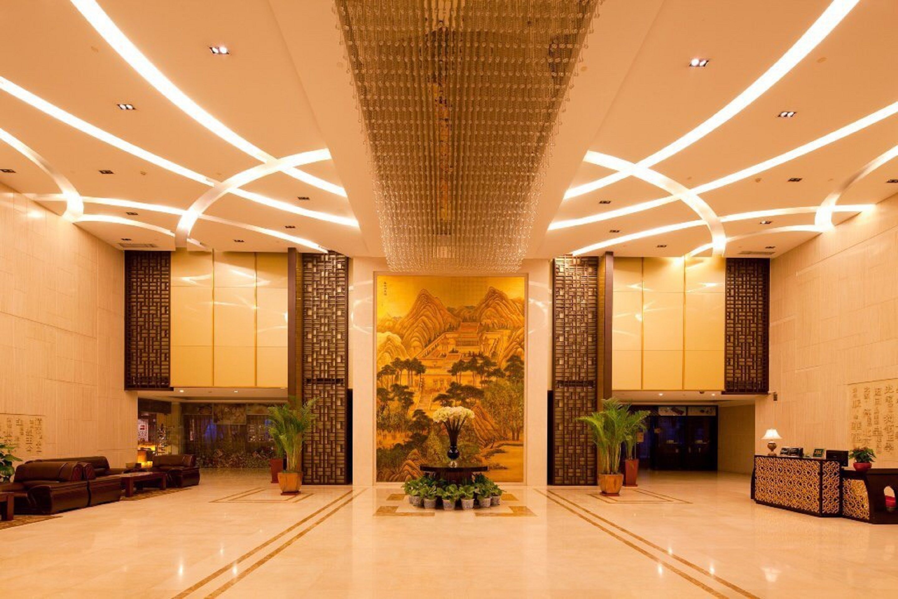 A spacious lobby with a traditional mural, a reception desk, and seating areas.