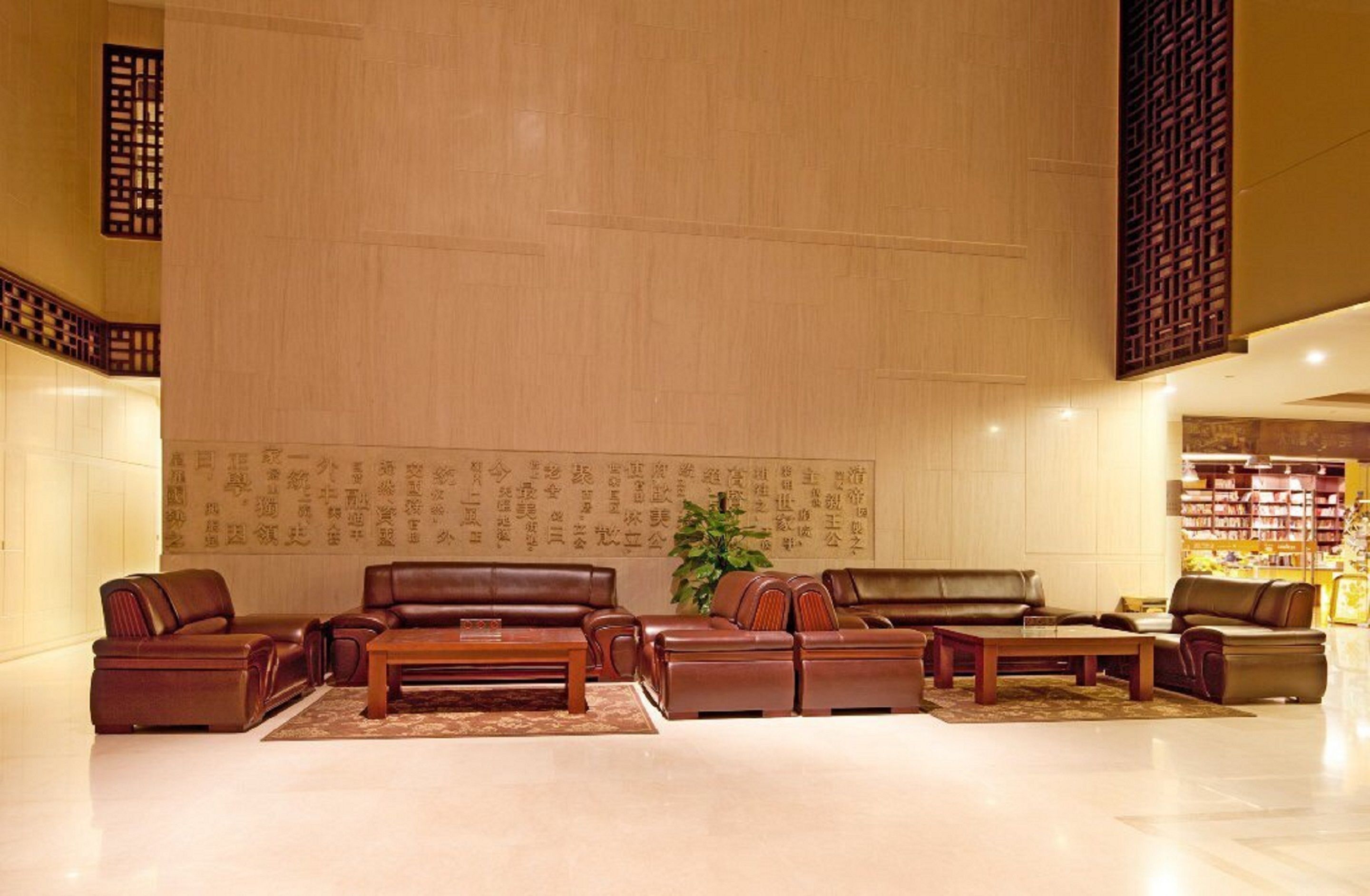 Eine großzügige Lobby mit Ledersofas, einem Couchtisch und einem großen Bücherregal.