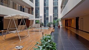A spacious atrium with a wooden floor, seating areas, and potted plants. - Wangfujing Xin Xiang Ya Yuan Apartment (Beijing)