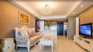 A modern living room with a sofa, coffee table, TV, and a chandelier. - Wangfujing Xin Xiang Ya Yuan Apartment (Beijing)