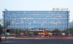 A modern multi-story building with a grid of windows, a prominent sign at the top, and a busy street in front. - Wangfujing Xin Xiang Ya Yuan Apartment (Beijing)
