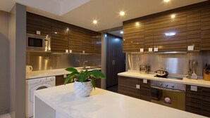 A modern kitchen with stainless steel appliances, wooden paneling, and a central island with a plant. - Wangfujing Xin Xiang Ya Yuan Apartment (Beijing)