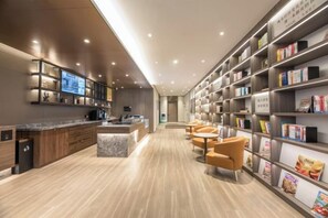 A modern library with bookshelves, a coffee station, and seating areas. - HanTing Hotel (Nantong Jinfeida Plaza) (Nantong)
