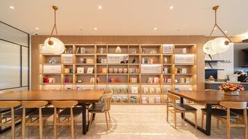 Une bibliothèque avec des étagères en bois, des lampes de lecture et un espace repas comprenant des tables et des chaises.