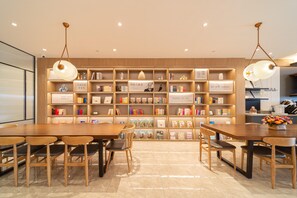 A library with wooden bookshelves, reading lamps, and a dining area with tables and chairs. - Hanting Hotel (Xiamen)