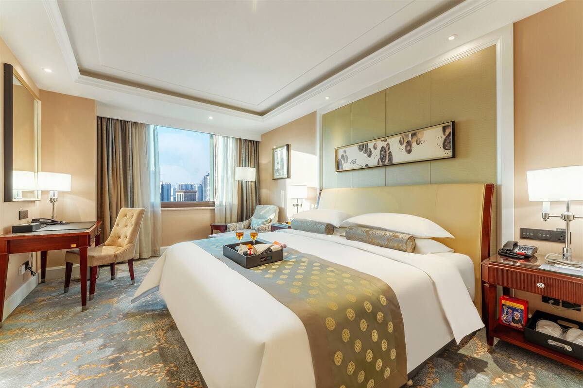Une chambre d’hôtel avec un grand lit, un bureau, une chaise et une vue sur la ville.