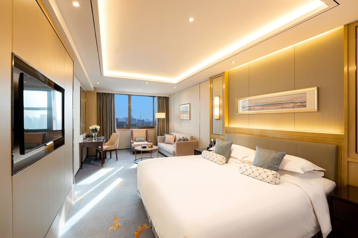 Une chambre d’hôtel avec un grand lit, un bureau avec une chaise, un canapé et une télévision.