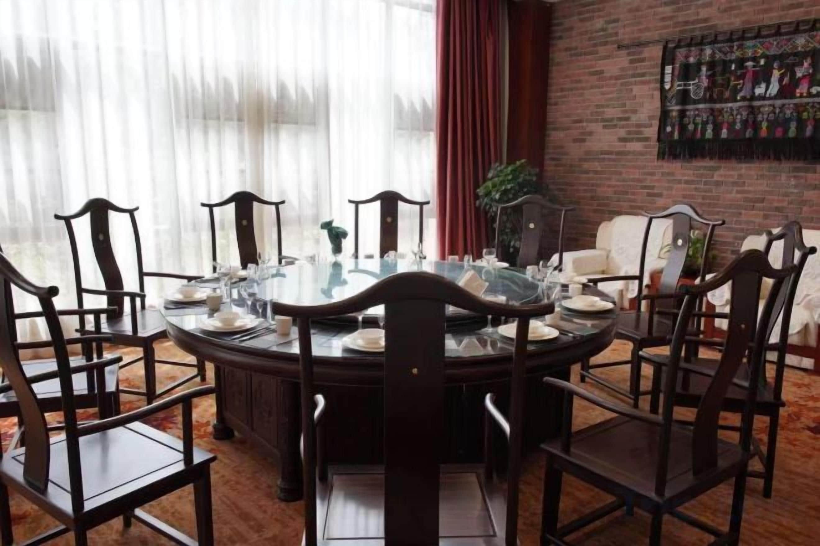 A round dining table with chairs, a glass top, and a central vase.