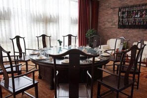 A round dining table with chairs, a glass top, and a central vase. - Maple Palace Hotel (Kunming)