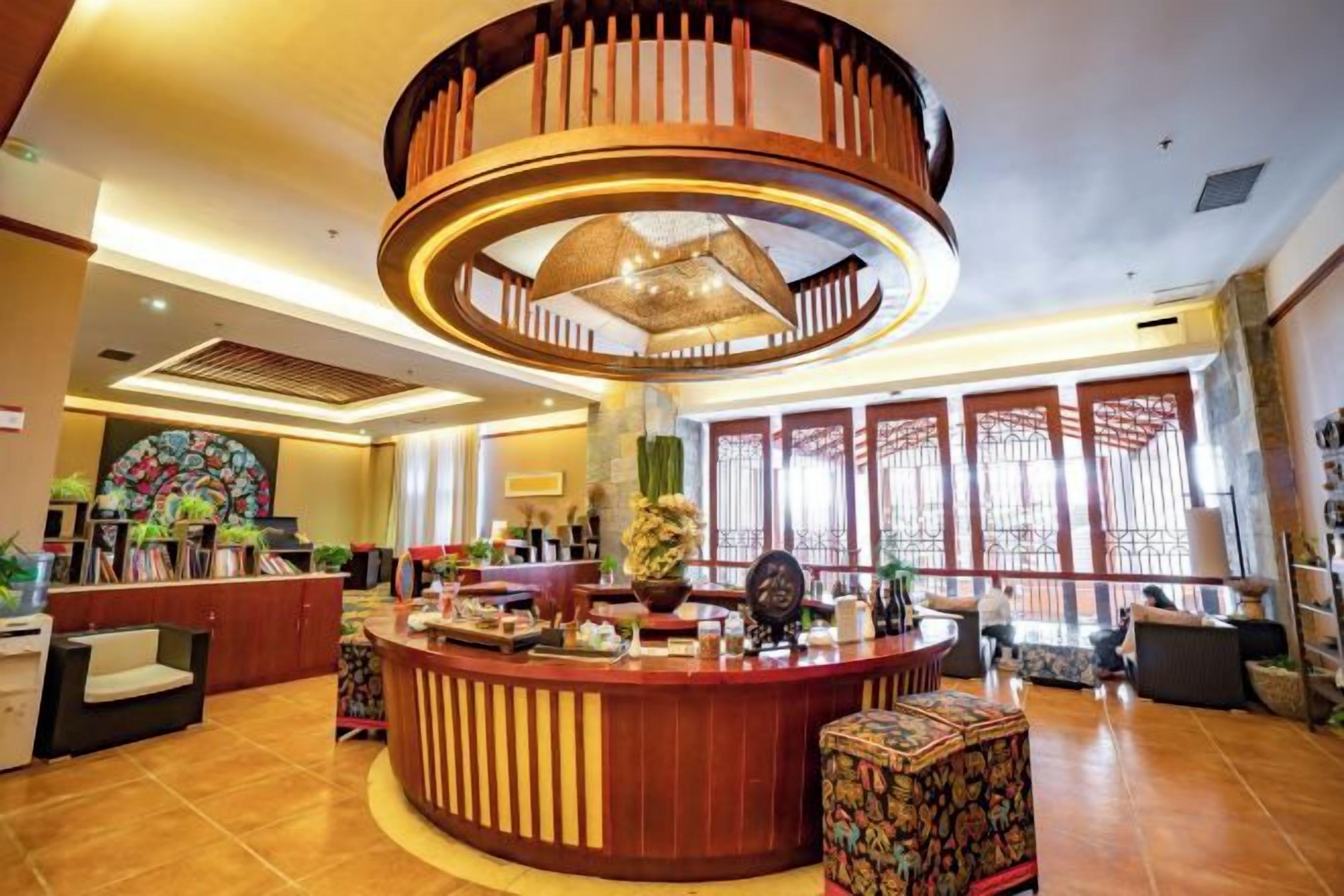 A hotel lobby with a central circular wooden structure, a reception desk, and a large window with traditional lattice design.