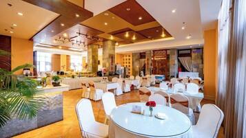 A spacious hotel lobby with round tables and chairs, a bar area, and a large seating area with a view of the interior.