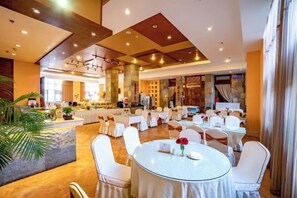 A spacious hotel lobby with round tables and chairs, a bar area, and a large seating area with a view of the interior. - Maple Palace Hotel (Kunming)