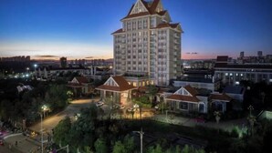A high-rise hotel with multiple floors, surrounded by smaller buildings and greenery. - Maple Palace Hotel (Kunming)