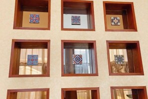 Une façade d’immeuble ornée de nombreuses fenêtres, chacune présentant un motif décoratif composé de carreaux encadrés.