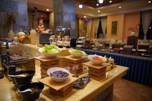 A buffet setup with various food items and serving utensils on a counter. - Maple Palace Hotel (Kunming)