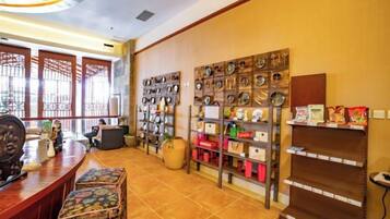 A reception area with a wooden desk, a patterned bench, and shelves with various items.