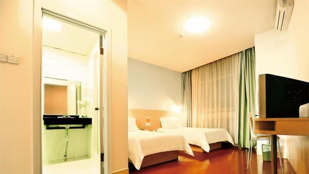 A hotel room with a bed, a desk, a television, and a bathroom with a mirror and sink. - Jinjiang Inn Style Taiyuan Exhibition Center (Taiyuan)