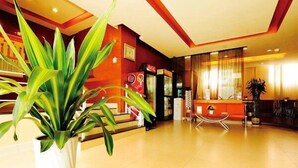 A hotel lobby with a large potted plant, a reception desk, and a seating area with a red sofa and chairs. - Jinjiang Inn Style Taiyuan Exhibition Center (Taiyuan)