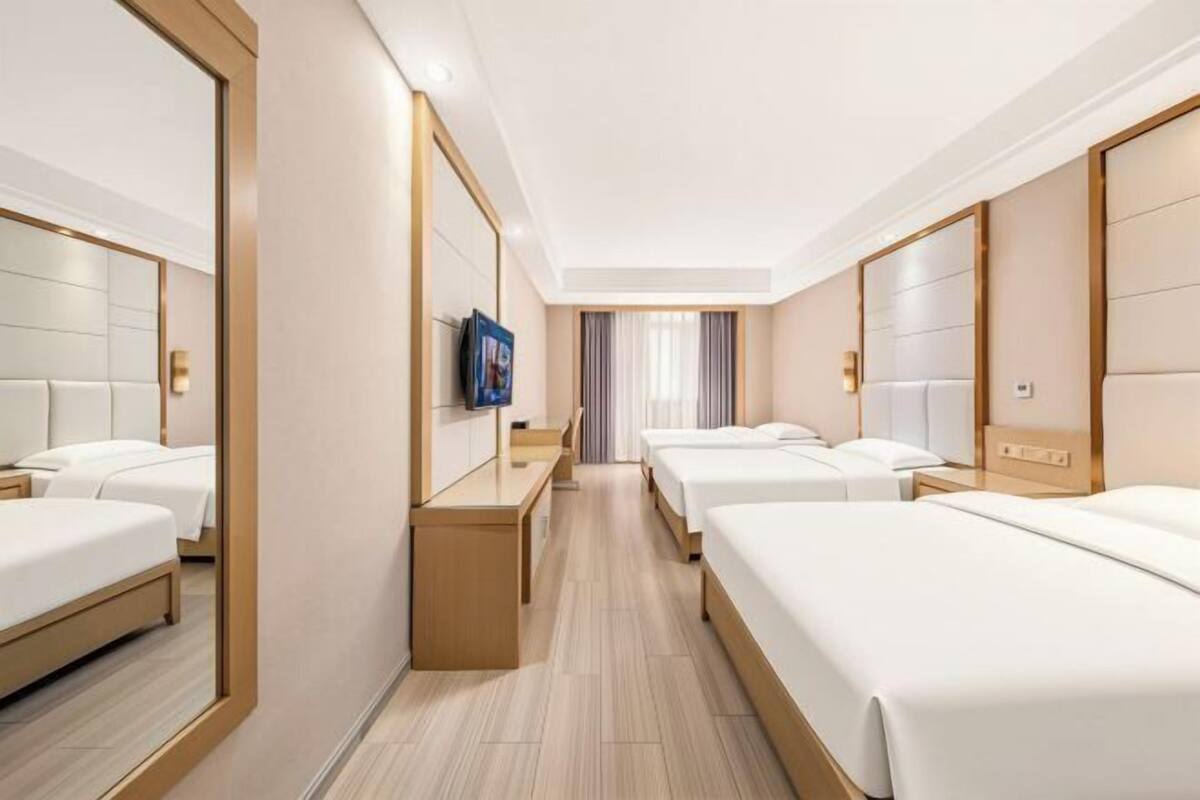 A hotel room with a central seating area, two beds, a TV, and a mirror.