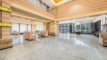A spacious lobby with a polished floor, seating areas, and a large window providing natural light.