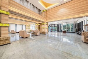 A spacious lobby with a polished floor, seating areas, and a large window providing natural light.