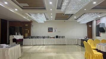 A banquet hall with a long table, yellow chairs, and a chandelier.