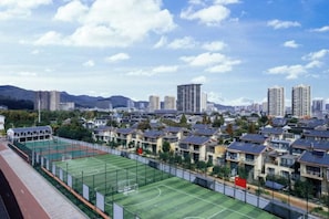 A residential area with a sports field, houses, and a cityscape in the background. - New Horizon Hotel (Luoping Sports Center, Qujing) (Qujing)