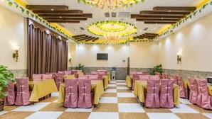 A banquet hall with checkered flooring, pink-covered tables and chairs, a chandelier, and a large window with curtains. - GreenTree Inn Guangzhou Chimelong Paradise Yuangang Metro Station Hotel (Guangzhou)
