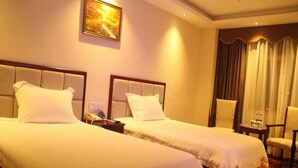A hotel room with two beds, a painting on the wall, a chair, and a table with a lamp. - GreenTree Inn Guangzhou Chimelong Paradise Yuangang Metro Station Hotel (Guangzhou)