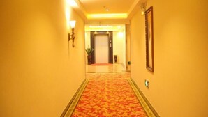 A hotel corridor with a carpeted floor, walls with light fixtures, and a door at the end. - GreenTree Inn Guangzhou Chimelong Paradise Yuangang Metro Station Hotel (Guangzhou)