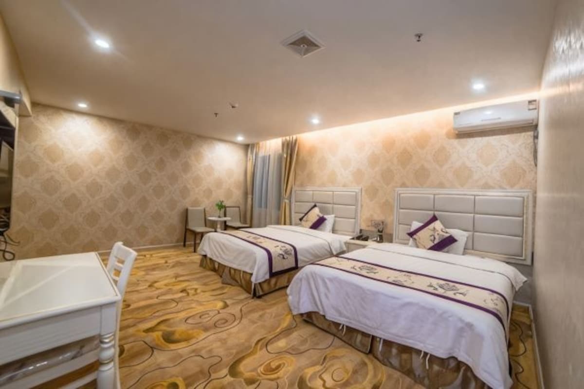 A hotel room with two beds, a desk, and a chair.