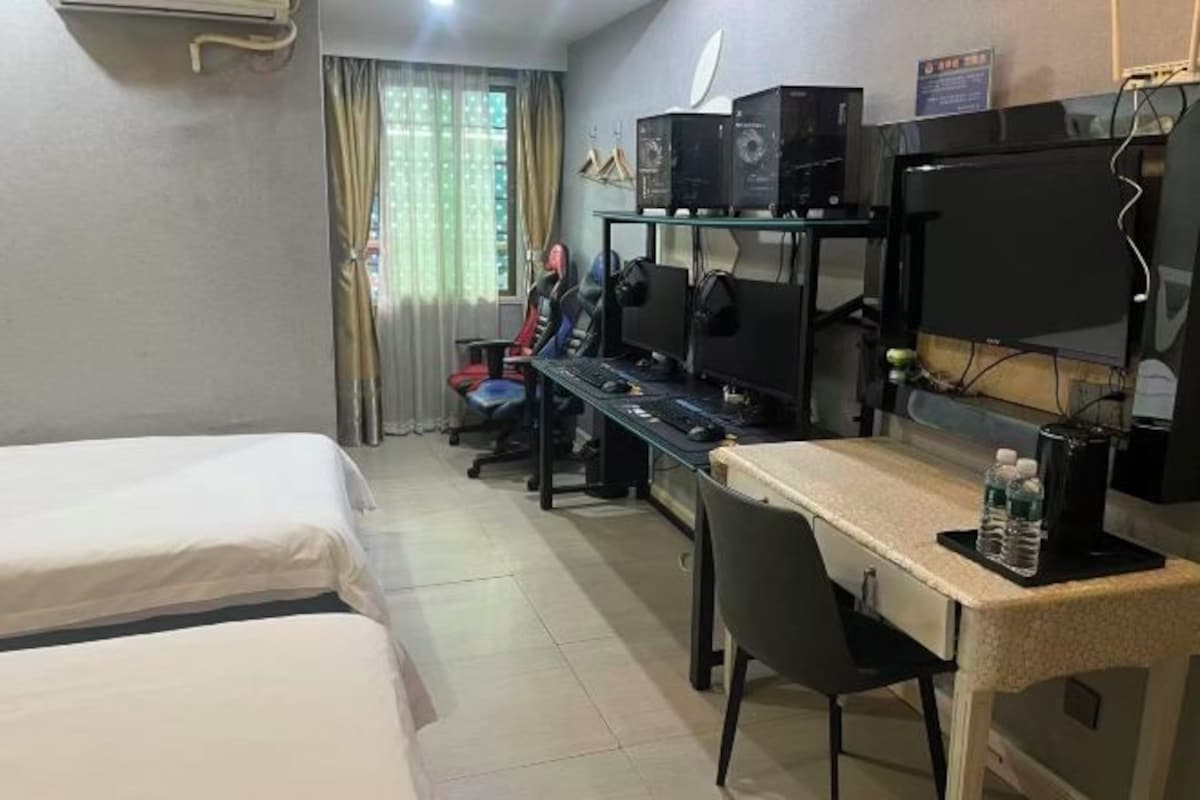 A hotel room with two beds, a desk with a computer, and a chair.